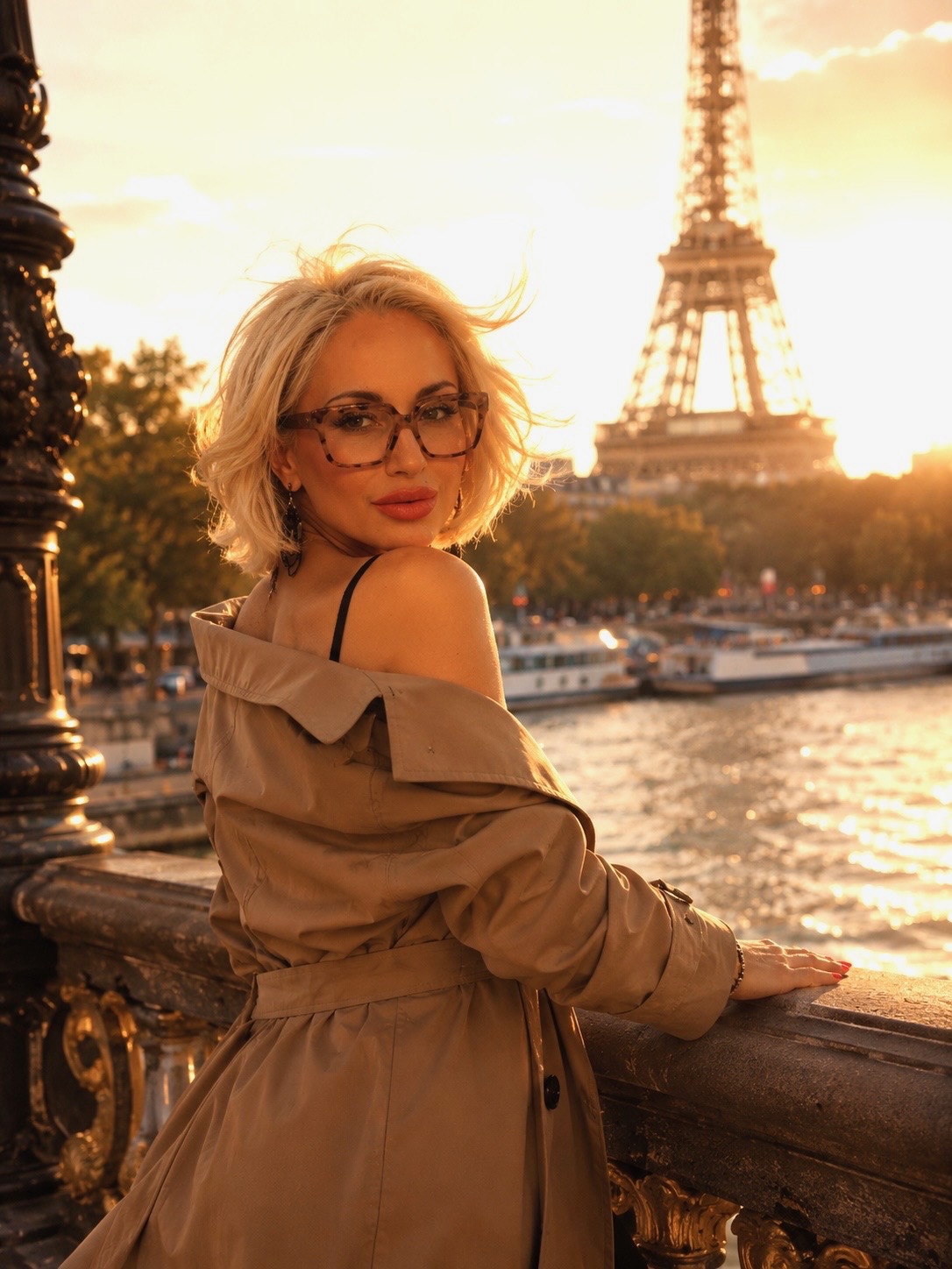 Yanita looking back over her shoulder at sunset on a Paris bridge, the Eiffel Tower glowing behind her